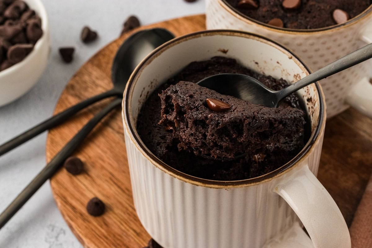 Spoon lifting a soft, moist bite of almond flour chocolate mug cake from a mug