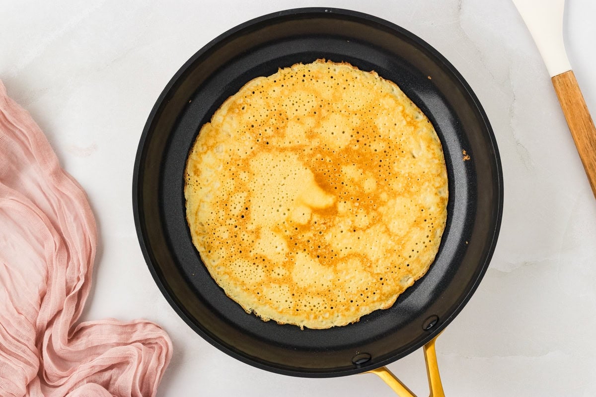 Almond flour crepe cooking on the second side until lightly golden