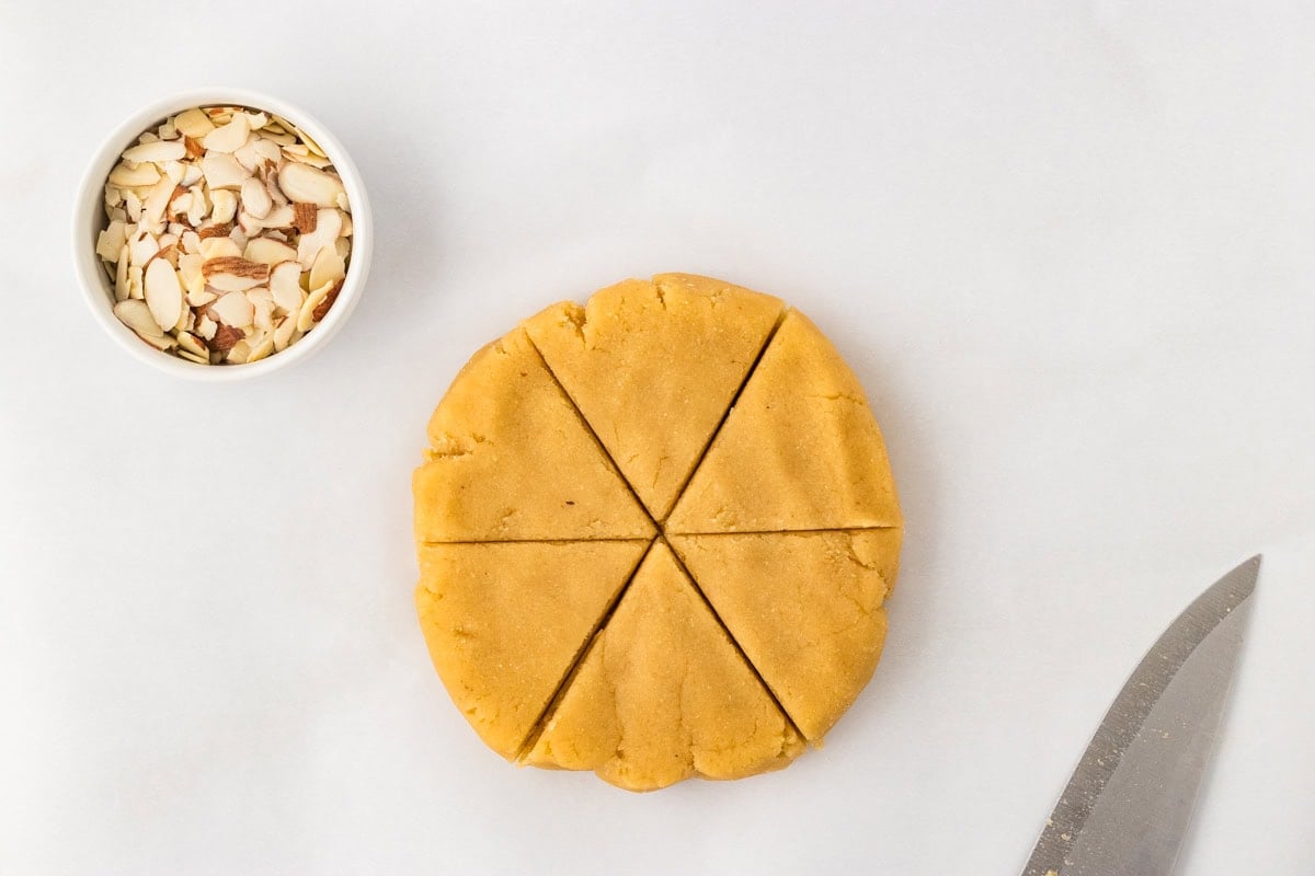 Almond flour scone dough shaped into thick disc and cut into 6 triangles with knife