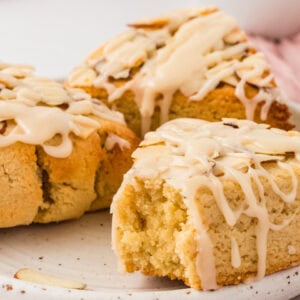 Close-up of almond flour scone with vanilla icing drizzle and sliced almonds showing soft crumb