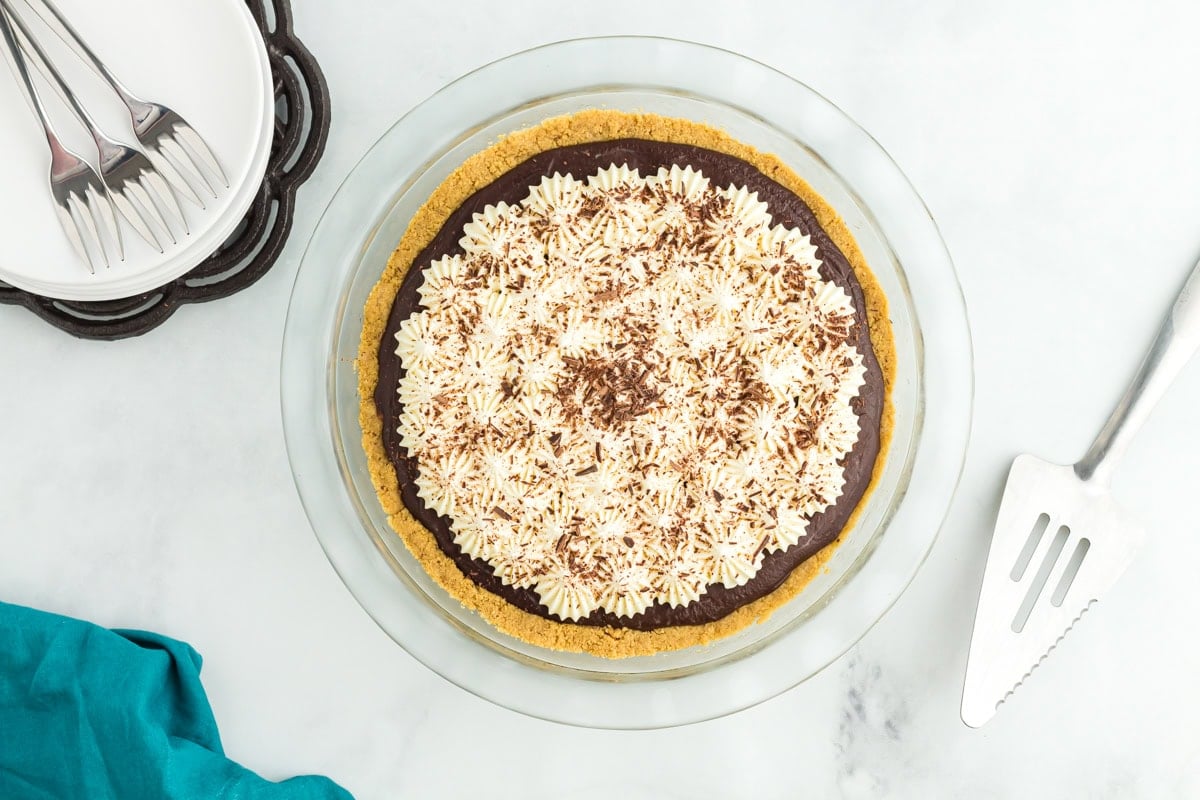 Gluten-free chocolate pie topped with whipped cream and chocolate shavings, ready to serve.