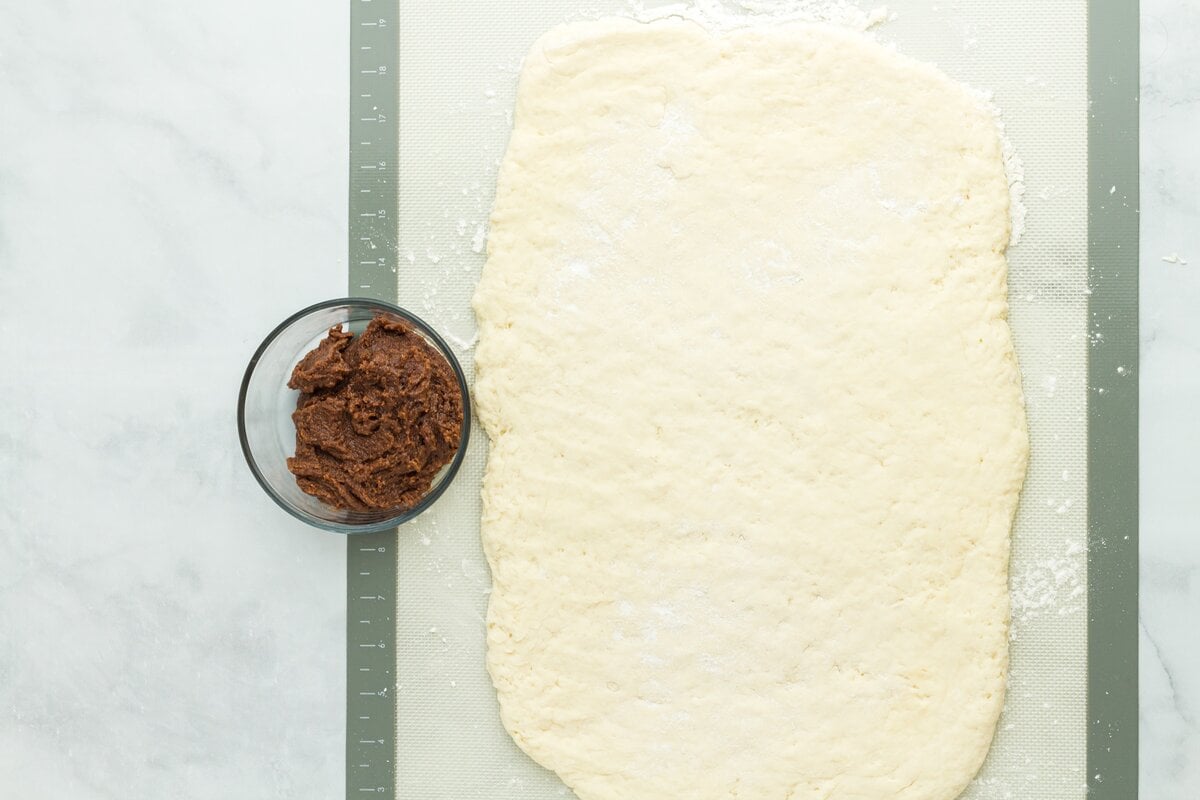 Gluten free dough rolled into a rectangle on a silicone mat with filling nearby.