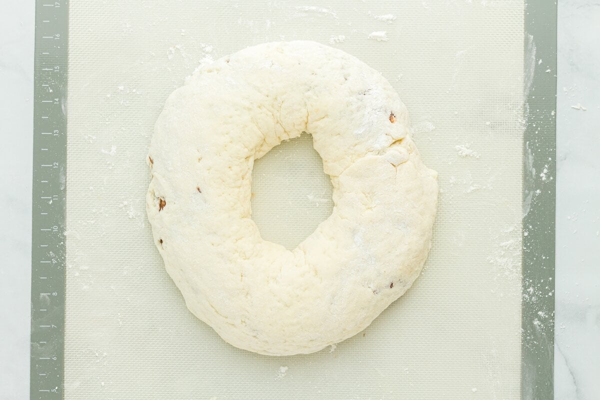 Gluten free king cake dough shaped into a ring on a floured silicone mat before baking.