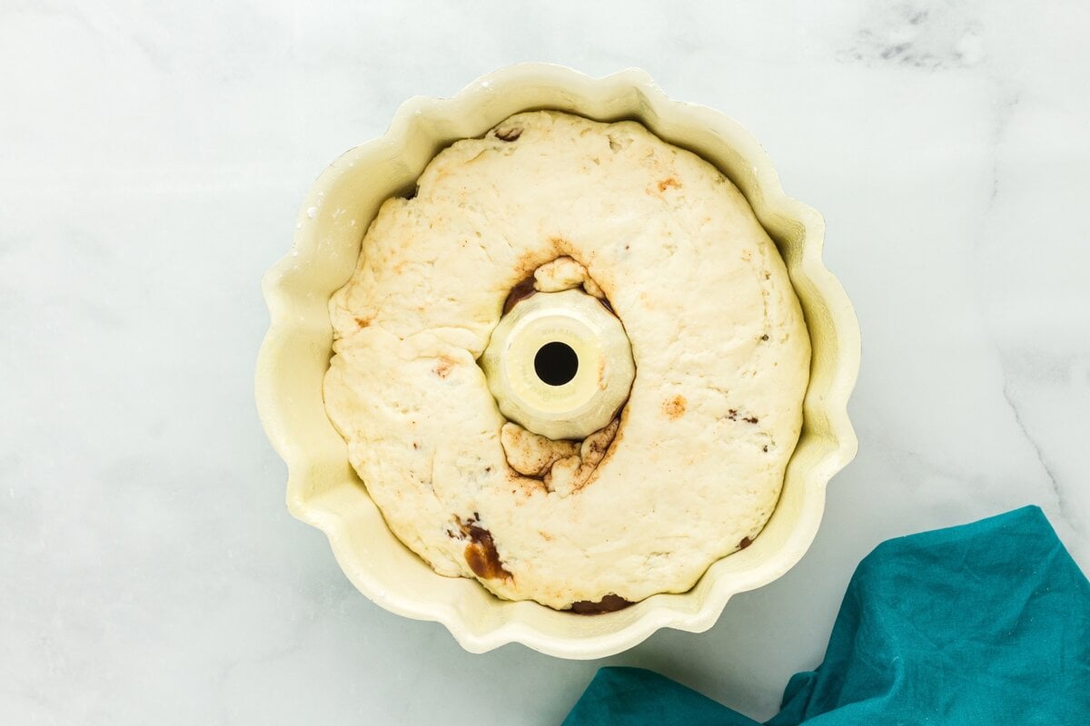 Shaped gluten free king cake dough placed inside a greased bundt pan before the second rise.