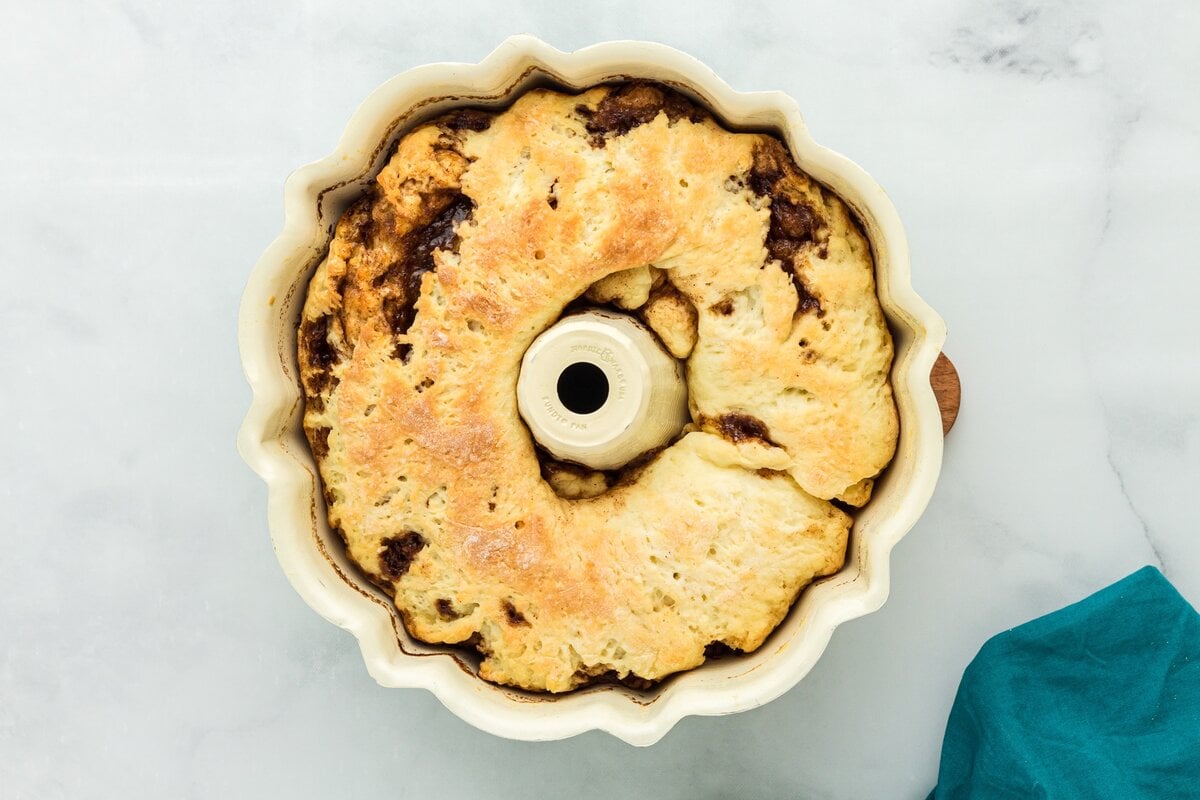 Baked gluten free king cake in the bundt pan with golden brown edges and visible cinnamon filling.