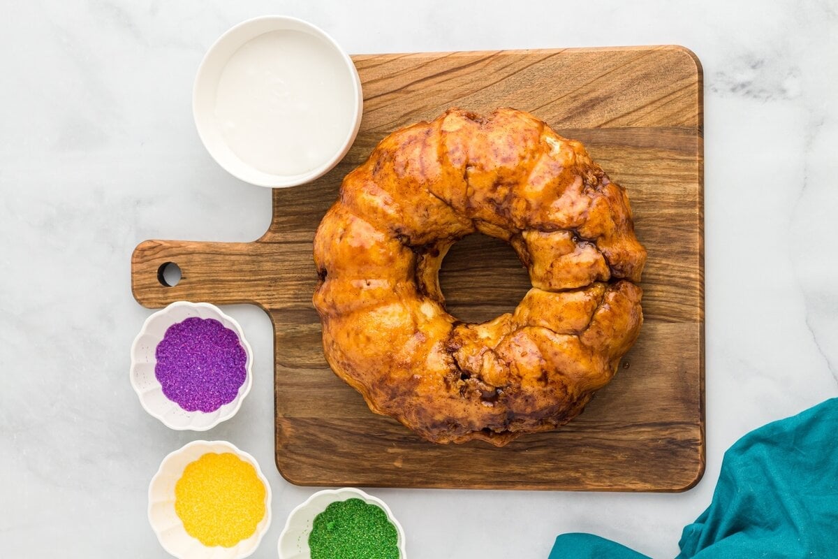 Baked gluten free king cake flipped onto a wooden board, ready for glazing.