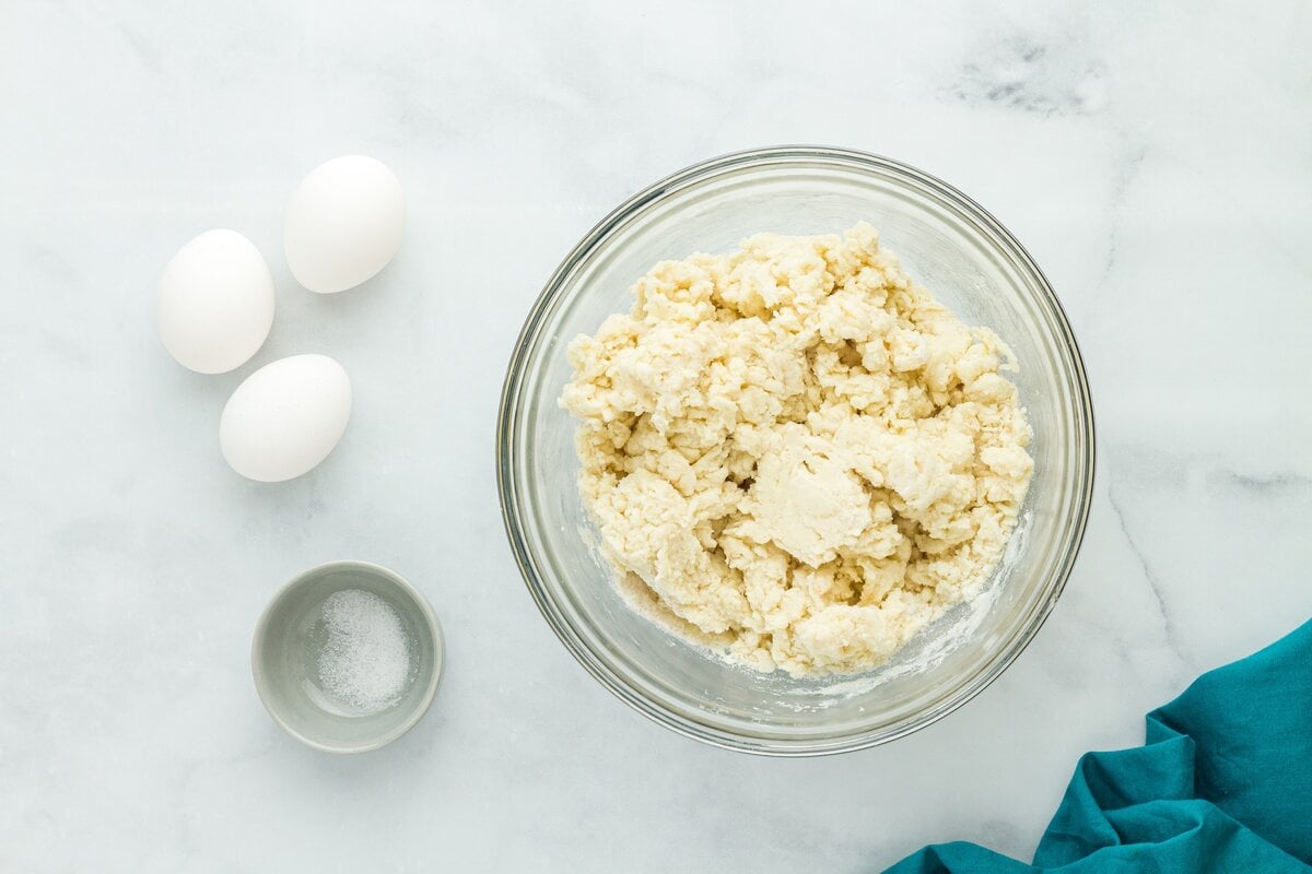 Gluten free dough mixture in a glass bowl with eggs and salt nearby before mixing.