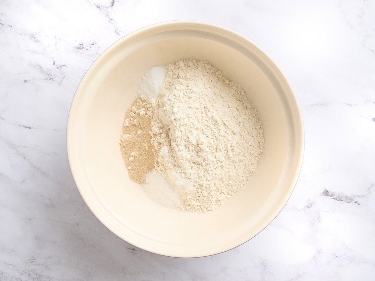Gluten-free flour, yeast, salt, sugar, and xanthan gum combined in a large mixing bowl before adding water.
