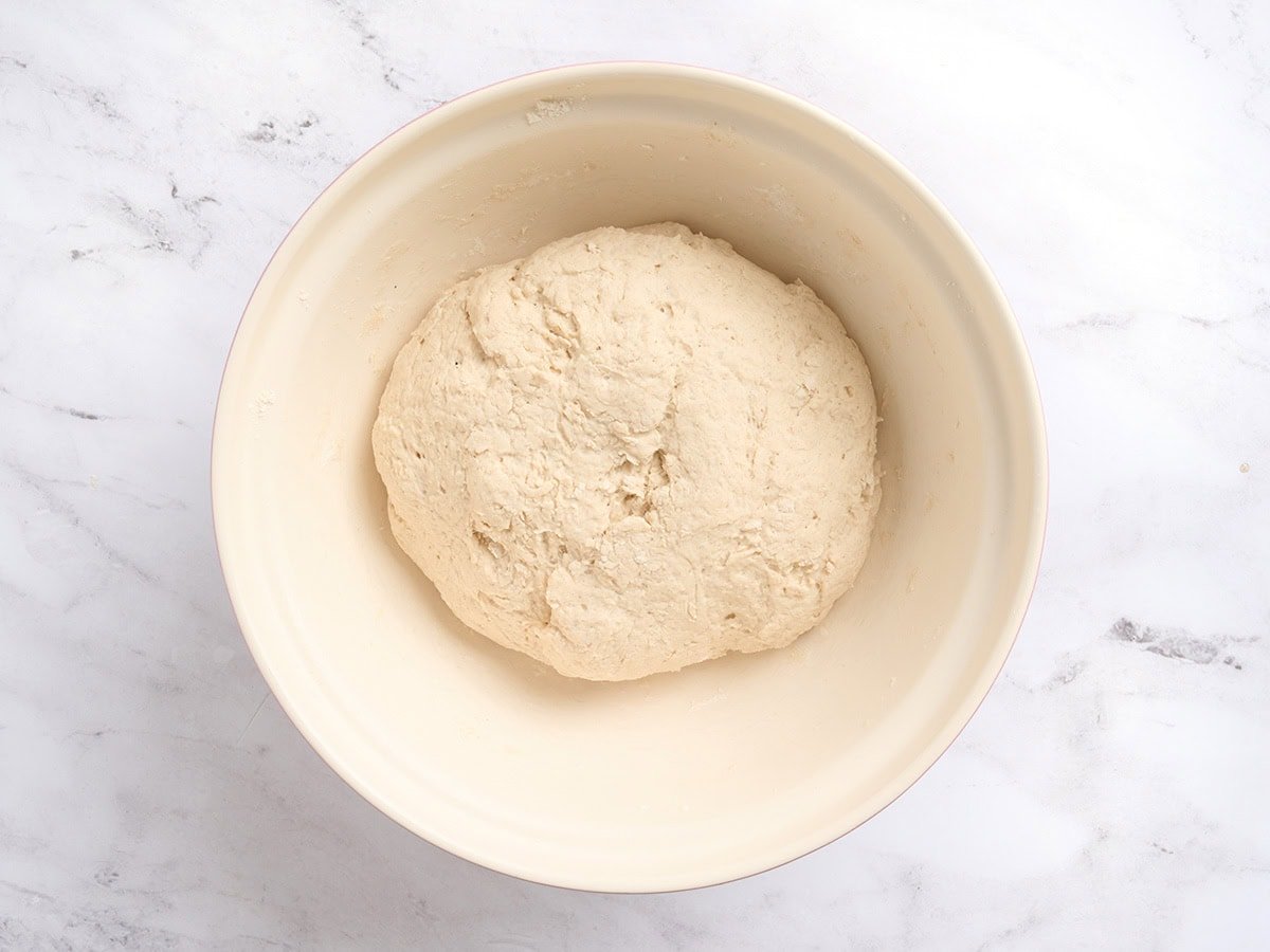 Gluten-free baguette dough after rising, slightly puffed and expanded in mixing bowl.