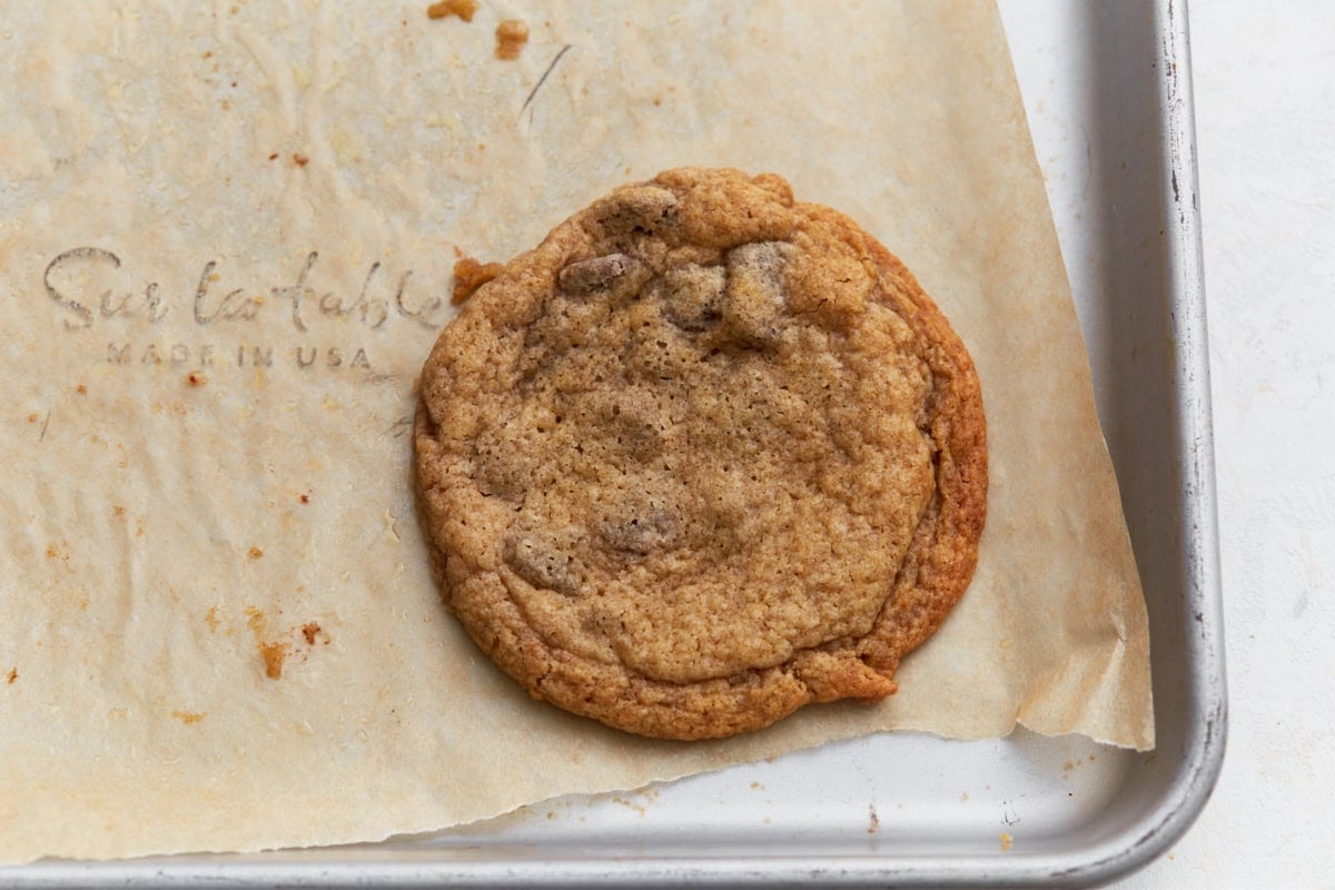 Single buckwheat chocolate chip cookie resting on parchment paper showing crisp edges and soft center