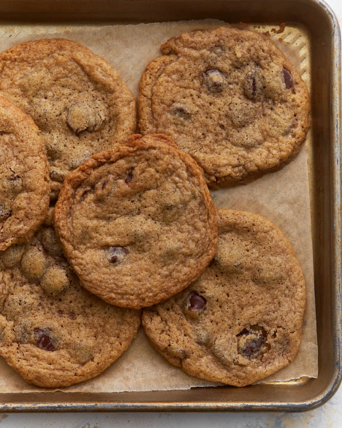 Baked buckwheat chocolate chip cookies cooling on a parchment lined baking sheet with crisp edges and soft centers