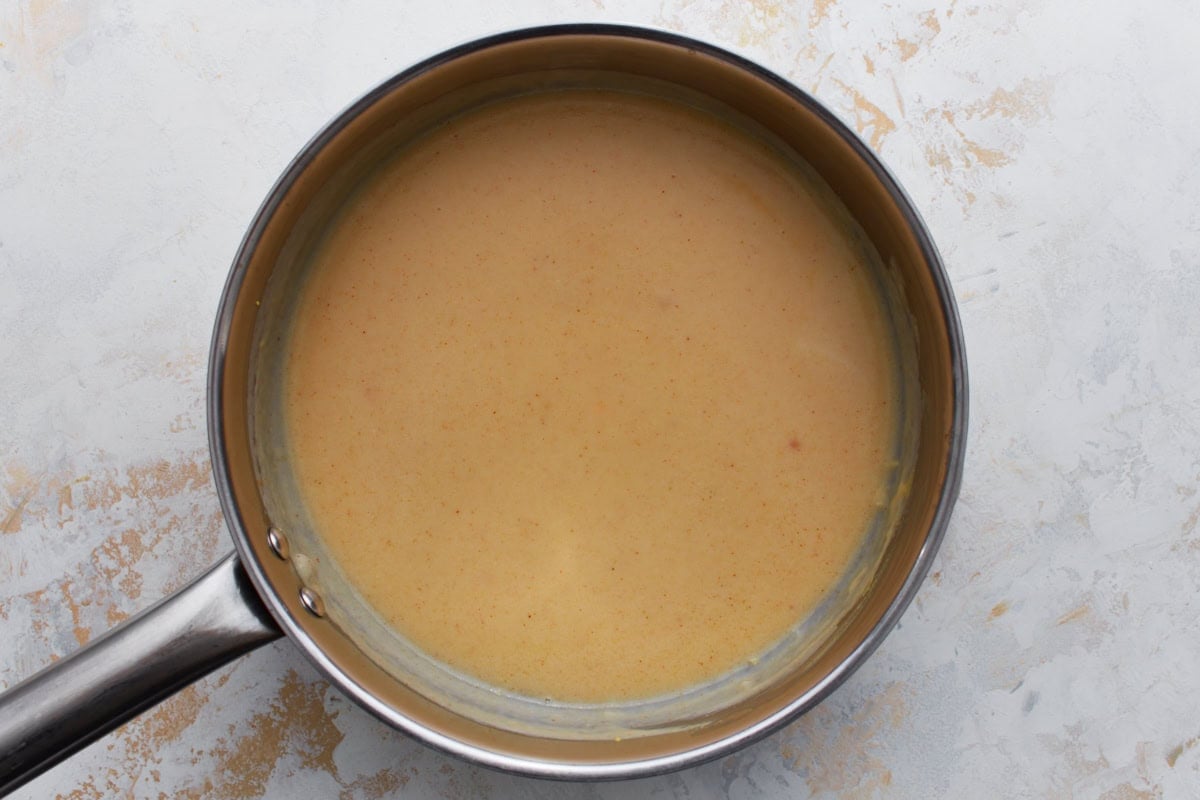 spices being stirred into gluten-free beer cheese sauce in a saucepan