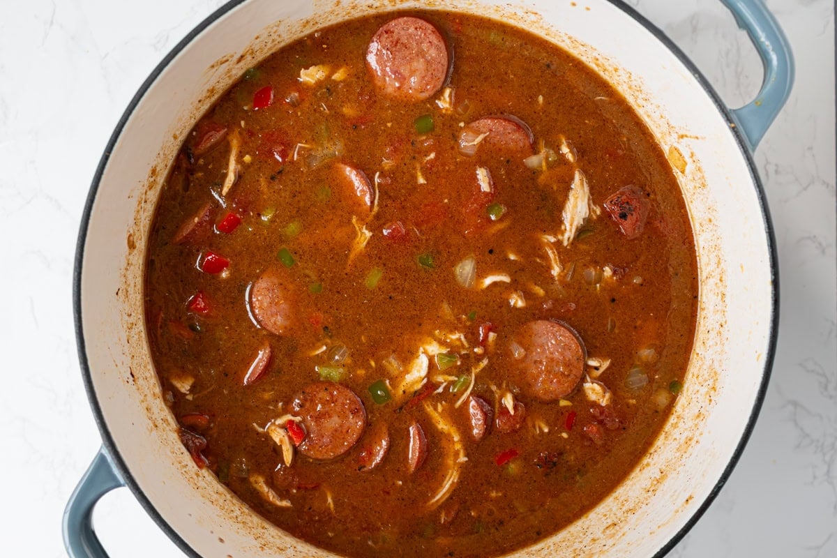 Chicken, sausage, vegetables, tomatoes, and broth added to the pot creating the full gumbo before simmering.