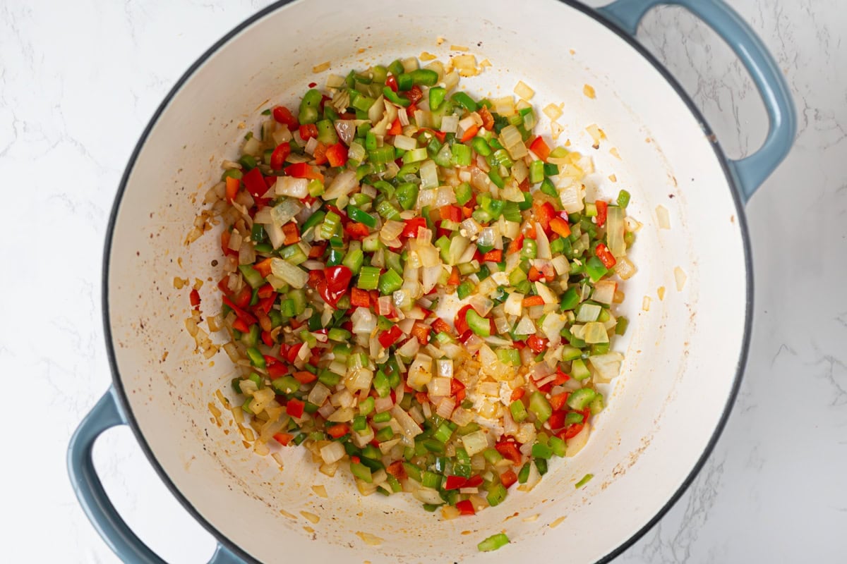 Diced onion, bell peppers, celery, and garlic sautéing in sausage drippings until soft and glossy.