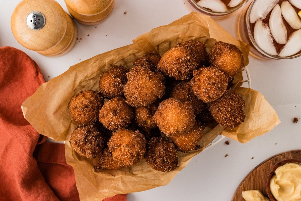 Basket lined with parchment paper filled with crispy gluten free hush puppies.