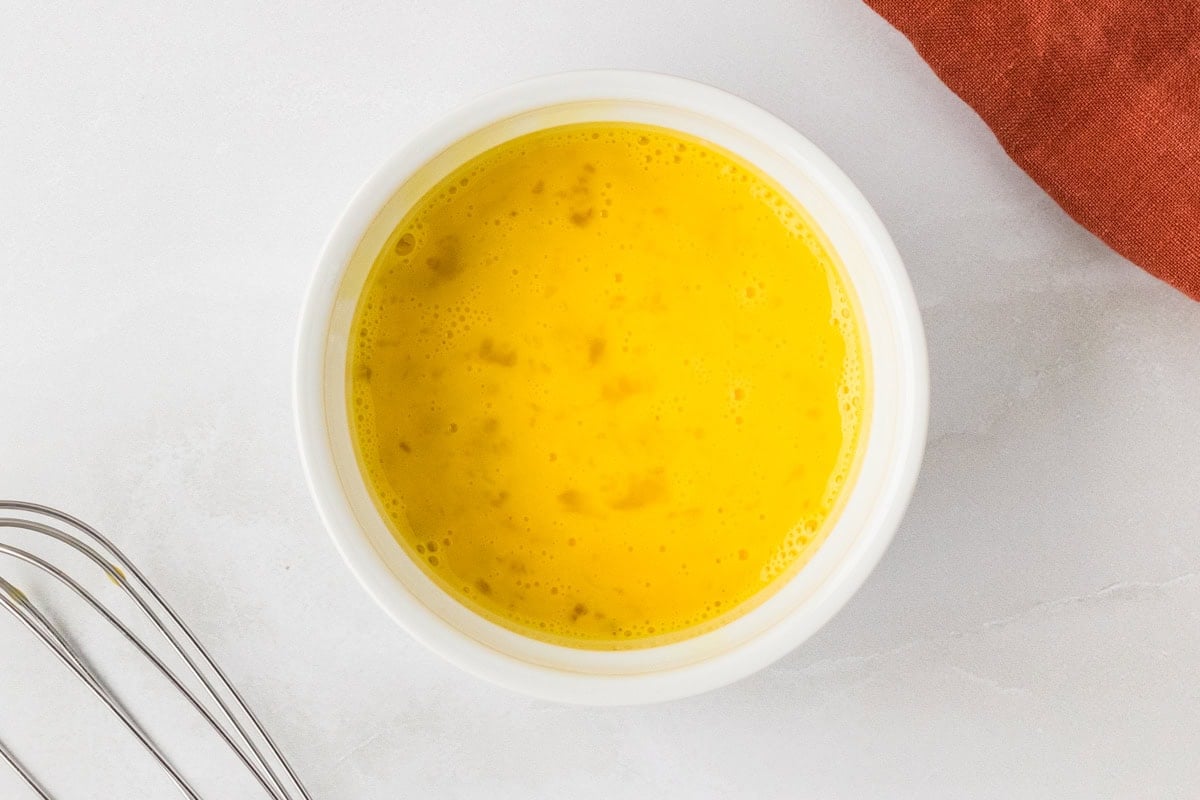 Beaten egg in a small bowl ready to be added to hush puppy batter.