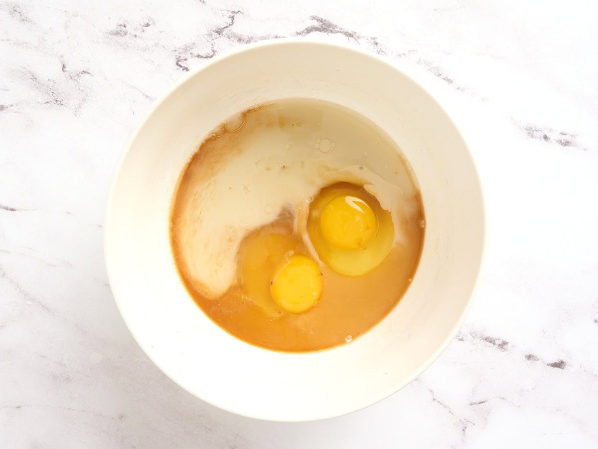 Eggs, oat milk, maple syrup, oil, and vanilla in a bowl before mixing for coconut flour pancake batter