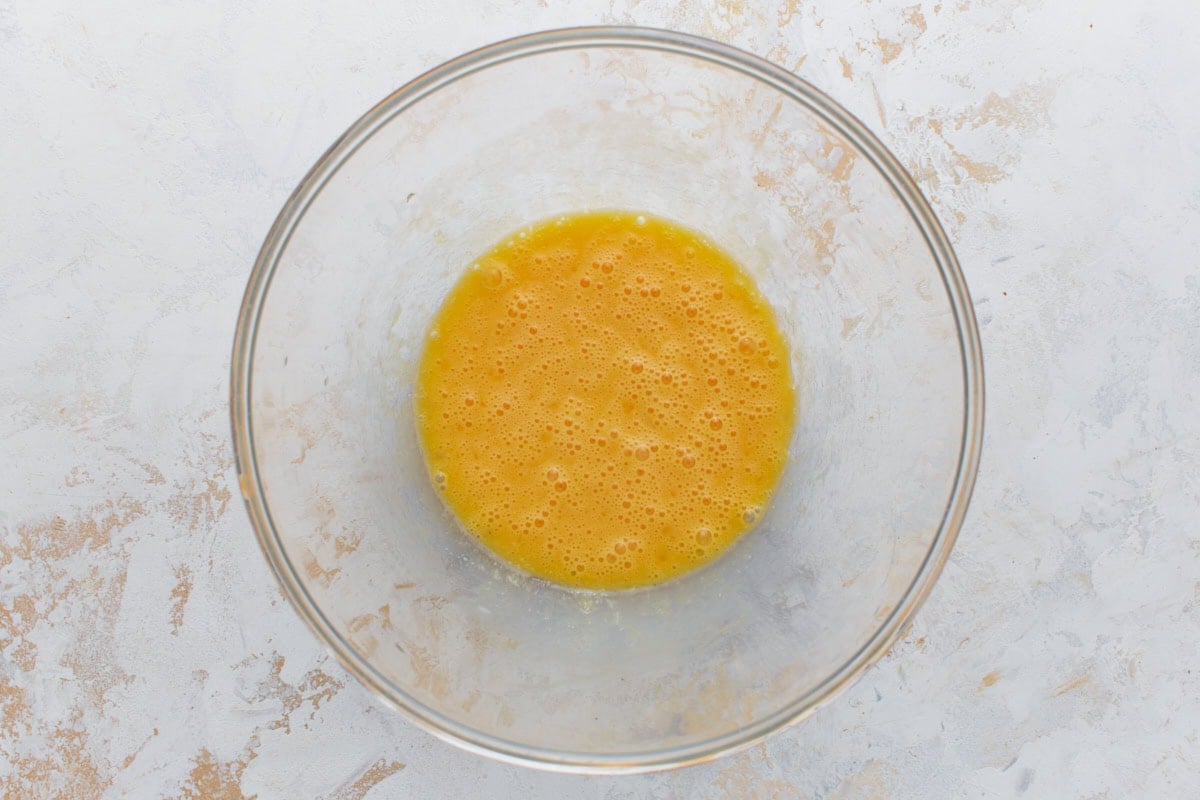 Eggs and melted butter whisked together in a glass bowl for almond flour biscotti dough