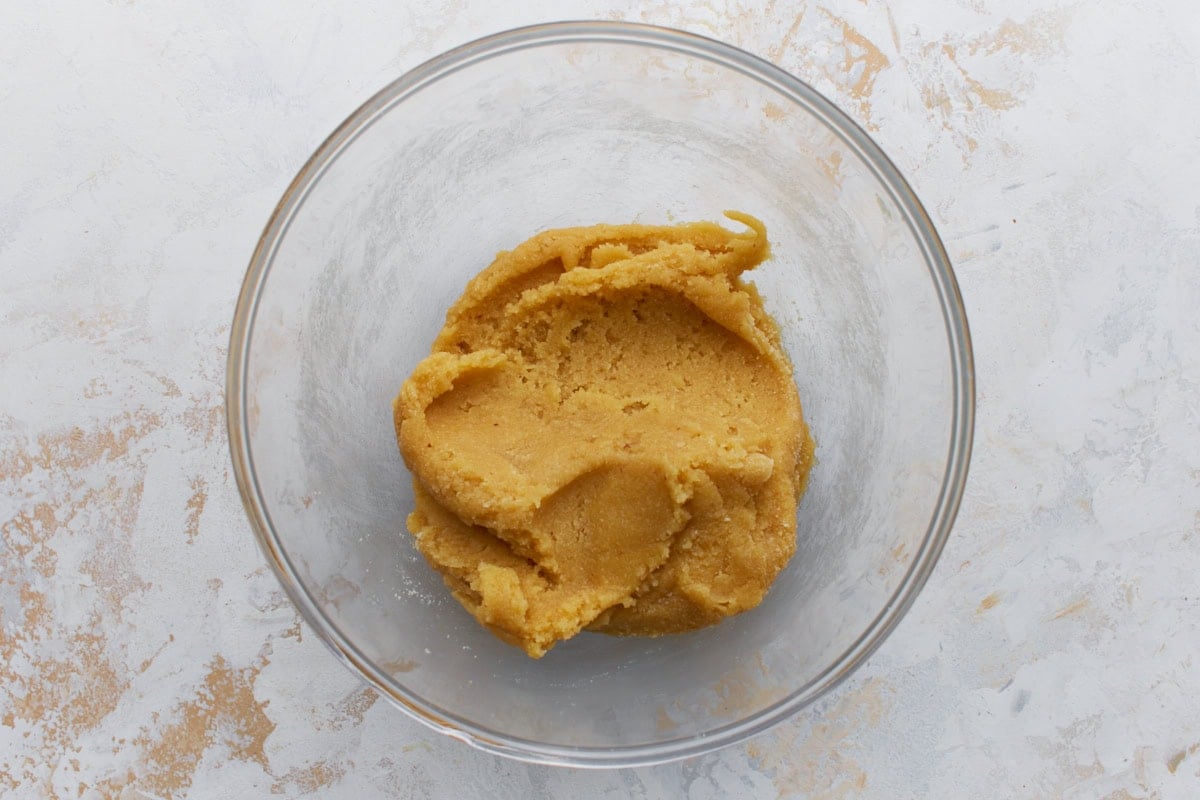 Thick almond flour biscotti dough mixed in a glass bowl before adding almonds and chocolate chips