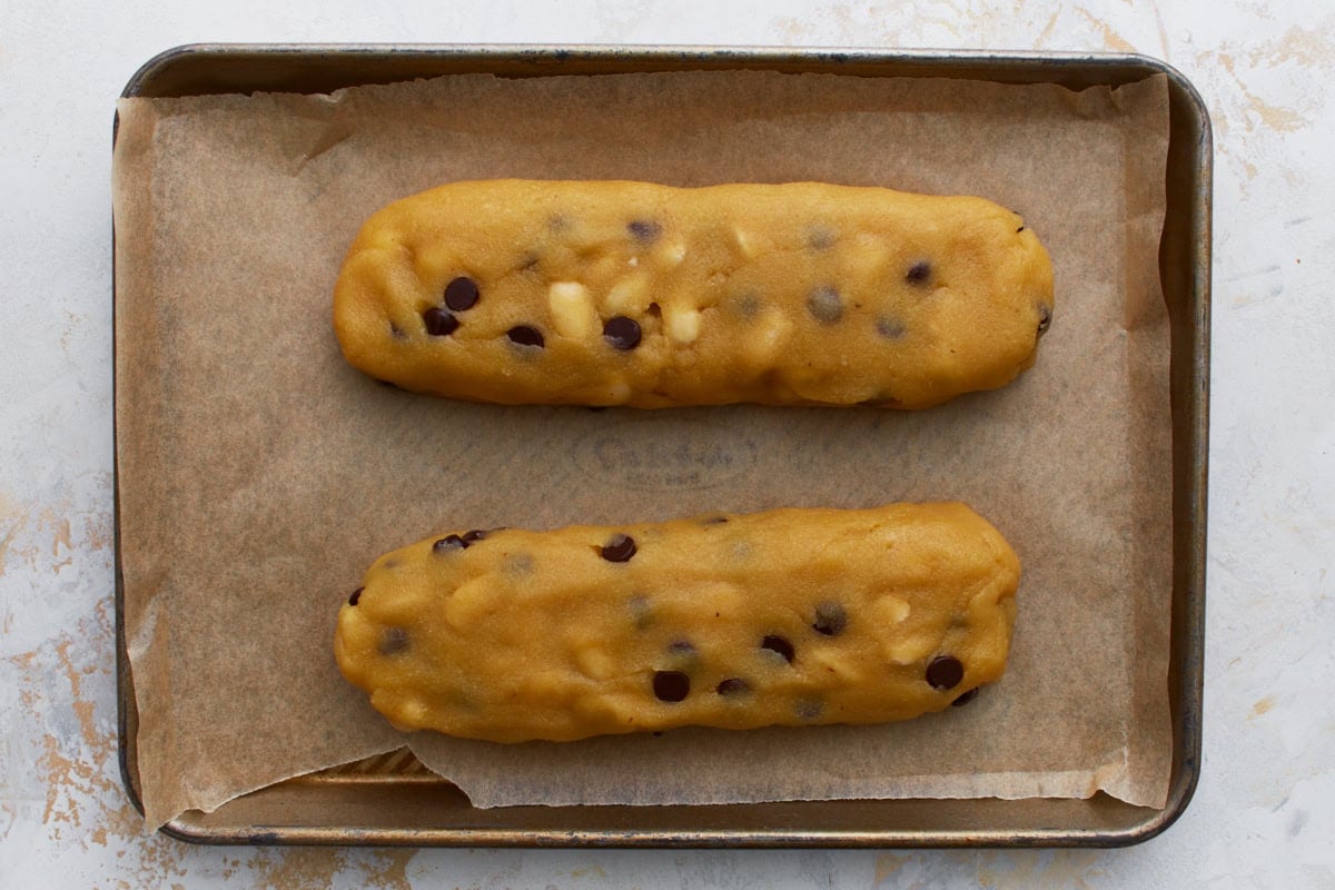 Two logs of almond flour biscotti dough shaped on a parchment-lined baking sheet before baking
