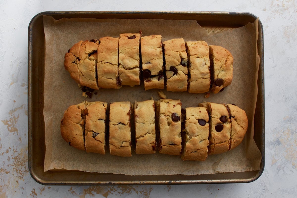 Baked almond flour biscotti logs sliced into pieces on a parchment-lined baking sheet
