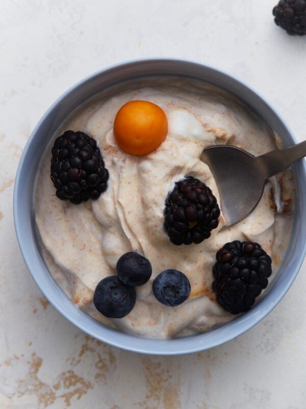 Dairy-free fruit dip topped with blackberries, blueberries, and a golden berry in a small bowl.