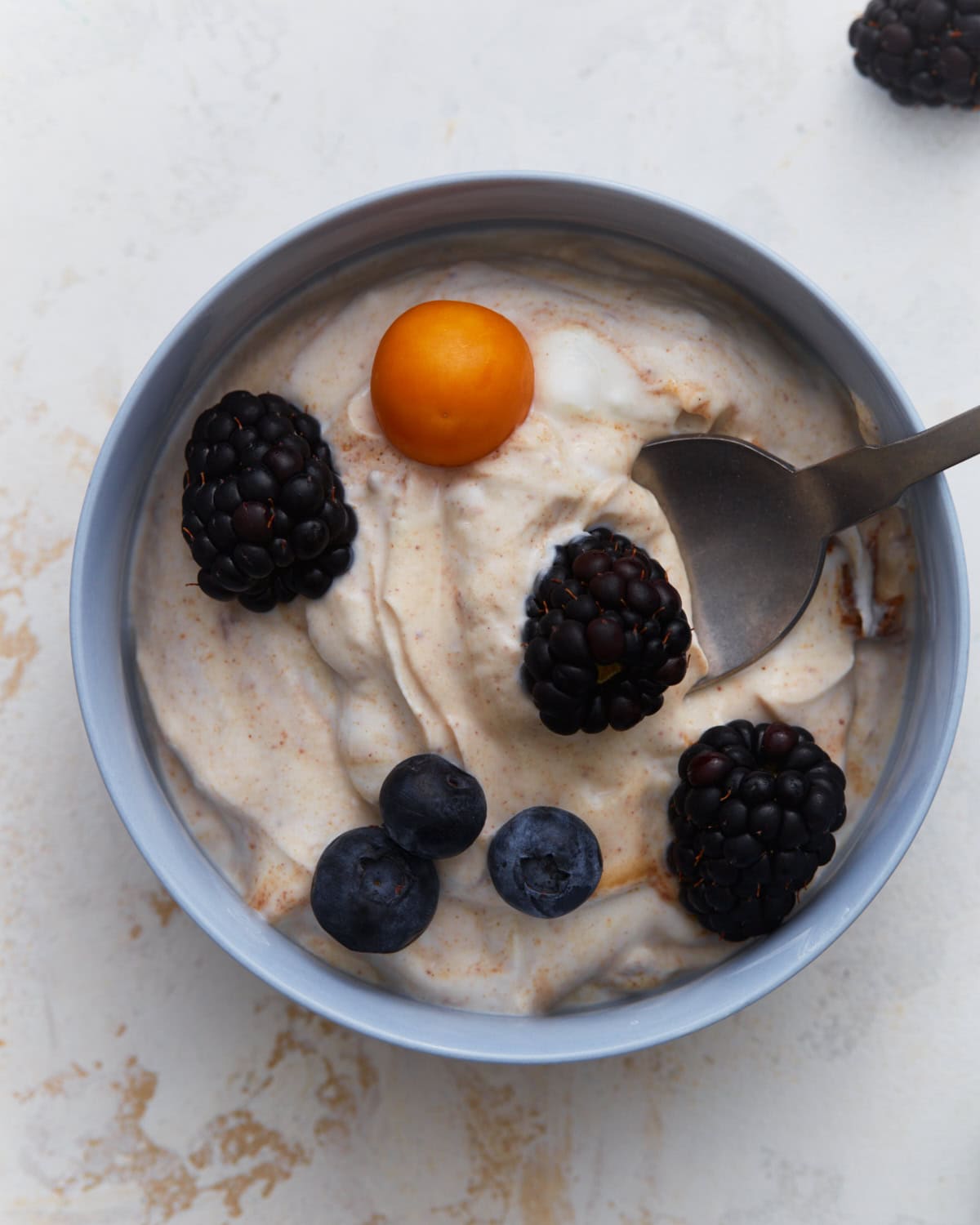 Dairy-free fruit dip topped with blackberries, blueberries, and a golden berry in a small bowl.