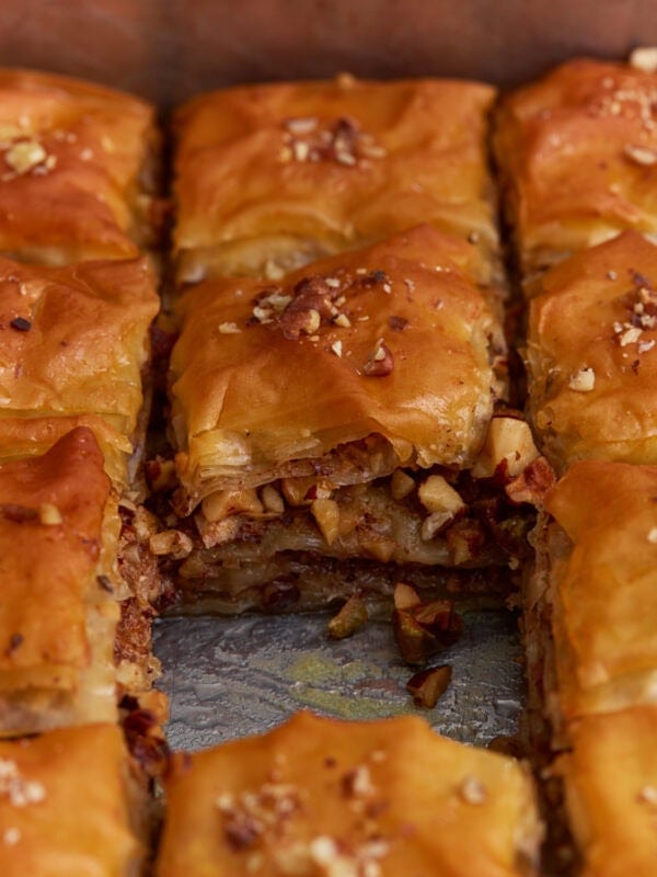 Gluten-free baklava cut into squares showing flaky phyllo layers and chopped nut filling soaked in honey syrup.
