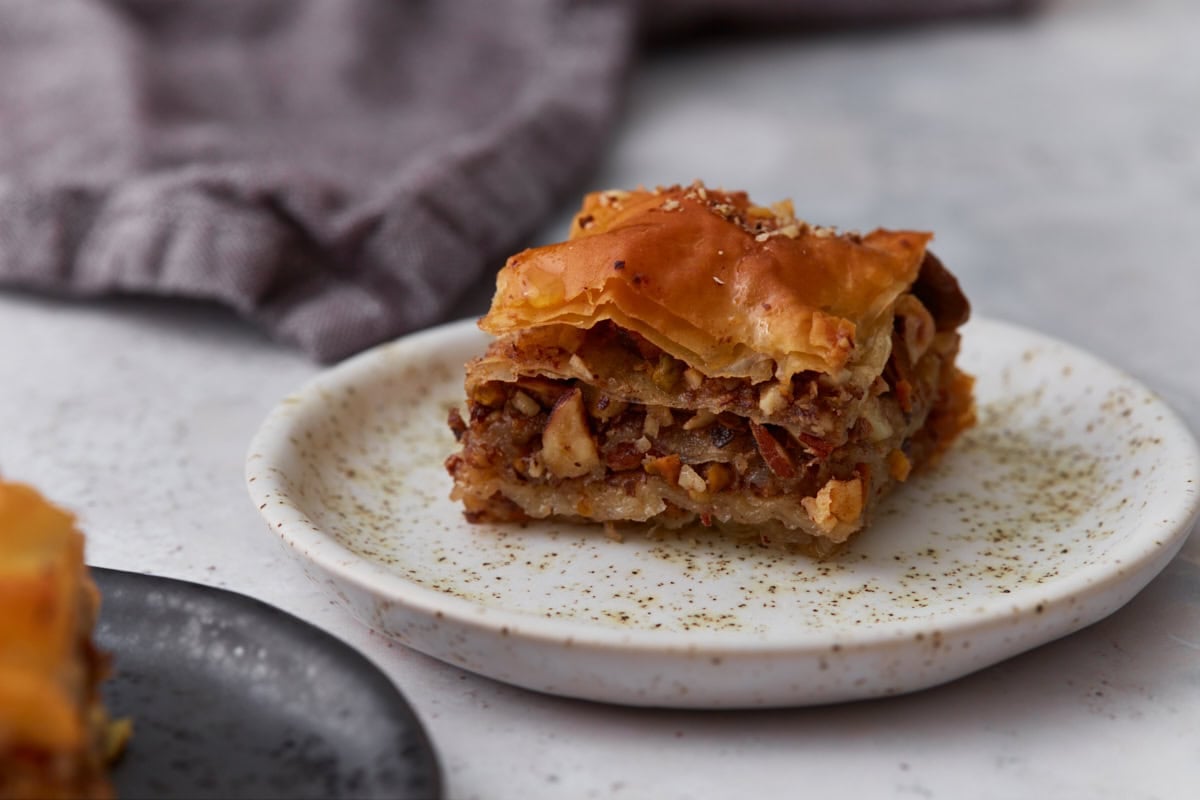 Piece of gluten-free baklava served on a small plate showing the layered nut filling and crisp phyllo pastry.