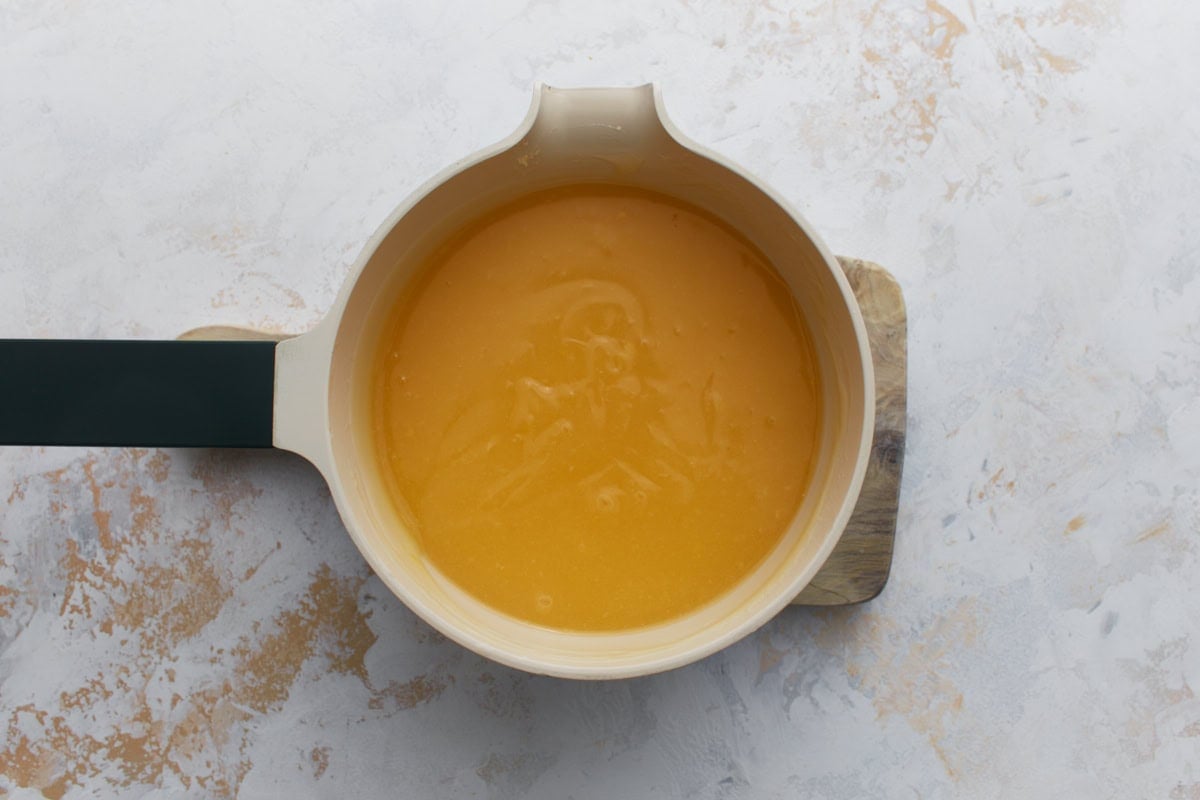 Lemon pie filling cooking in a saucepan until thick and glossy