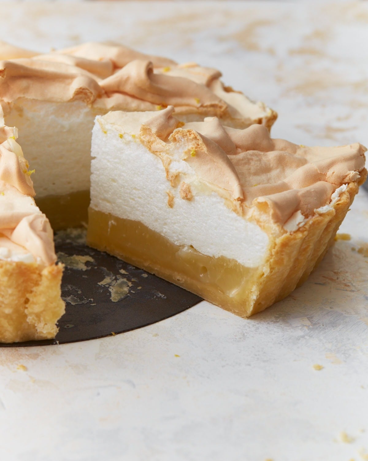Slice of gluten-free lemon meringue pie showing layers of lemon filling and fluffy toasted meringue