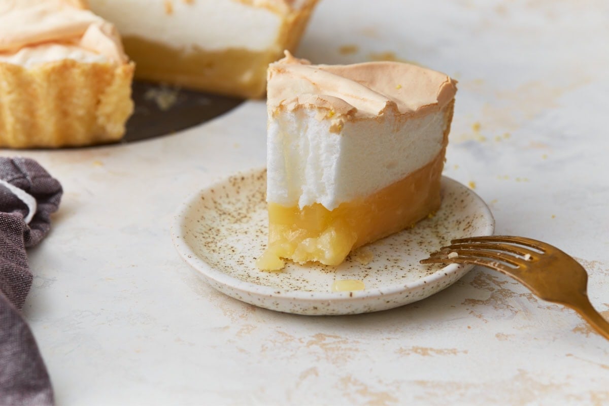 Slice of gluten-free lemon meringue pie with lemon filling and toasted meringue on a plate