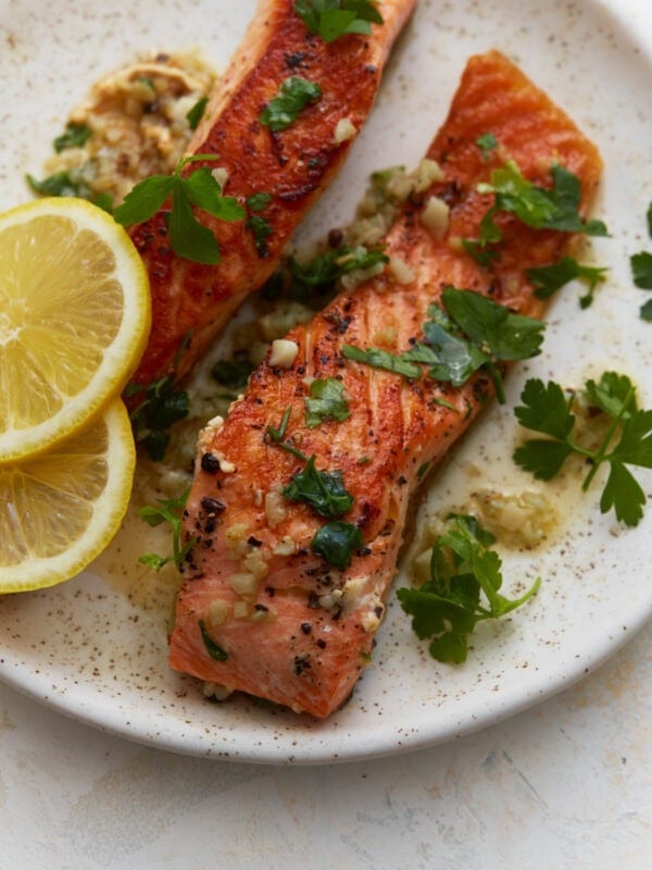 Keto salmon fillets with garlic butter sauce, fresh parsley, and lemon slices on a plate