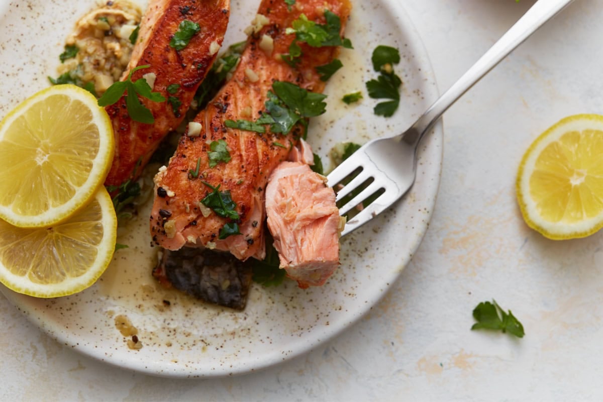 Close-up of flaky keto salmon being cut with a fork showing tender texture