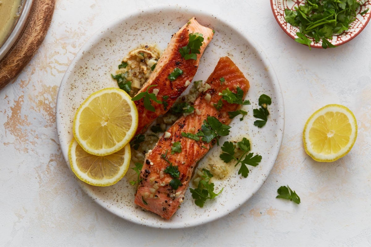Garlic butter salmon plated with lemon slices and fresh herbs