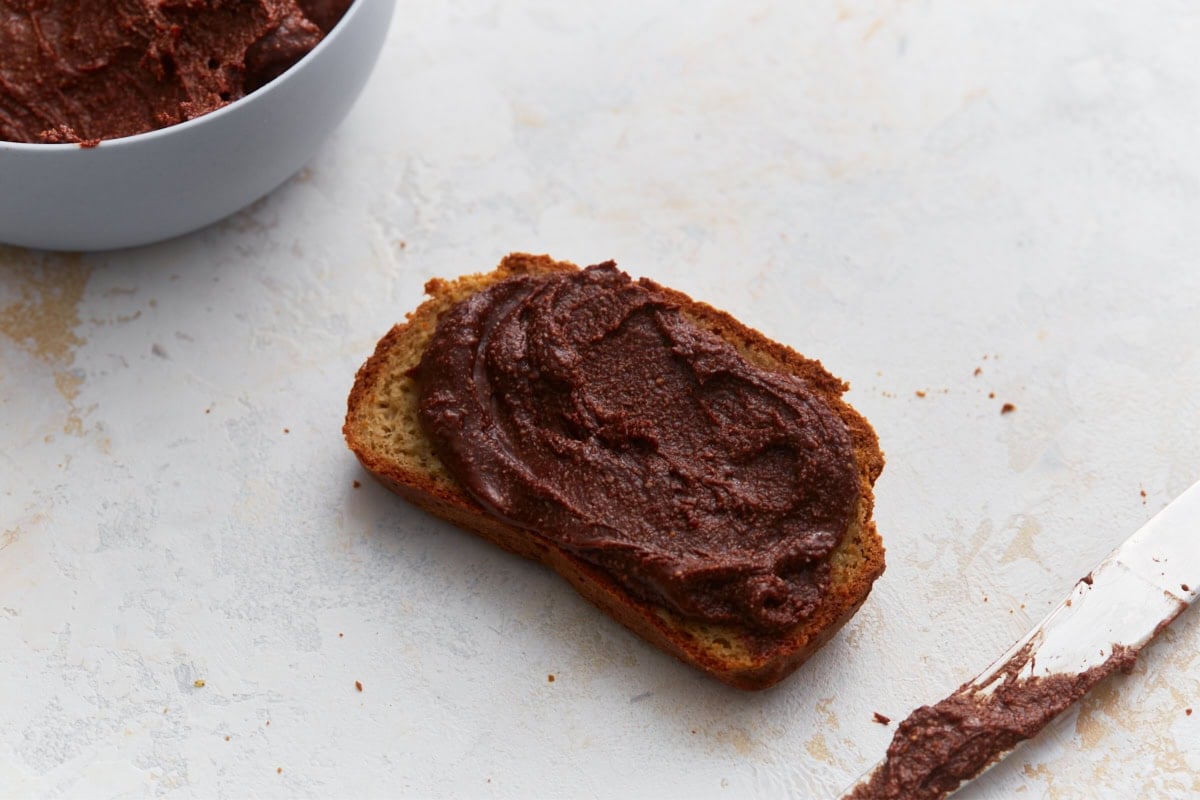 Slice of toast spread with vegan Nutella, showing thick and creamy chocolate hazelnut spread