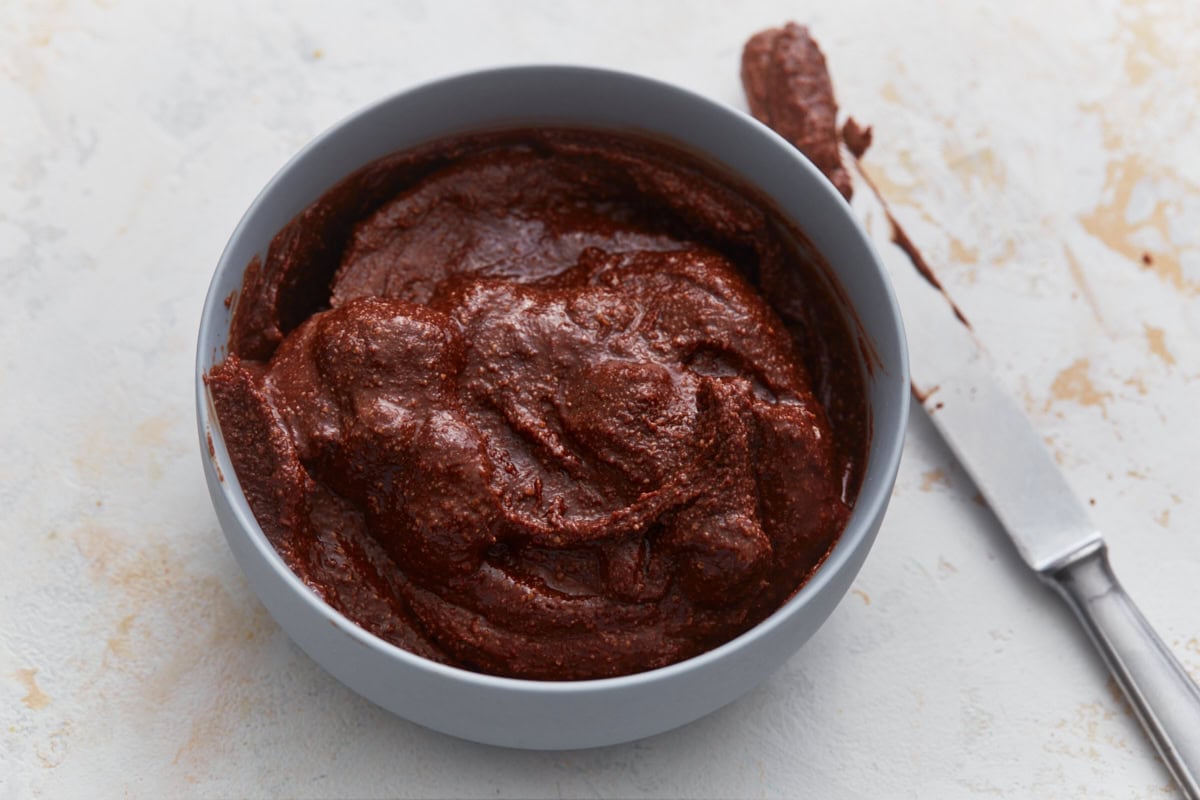 Homemade vegan Nutella in a bowl with a knife, showing smooth and spreadable texture