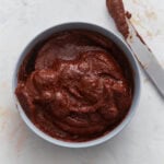 Creamy vegan Nutella in a bowl with a knife, showing thick, rich chocolate hazelnut spread texture