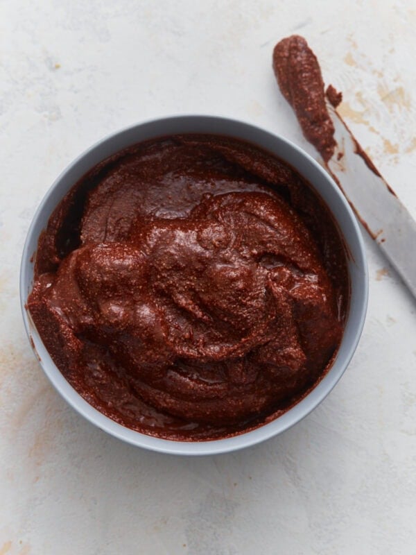 Creamy vegan Nutella in a bowl with a knife, showing thick, rich chocolate hazelnut spread texture