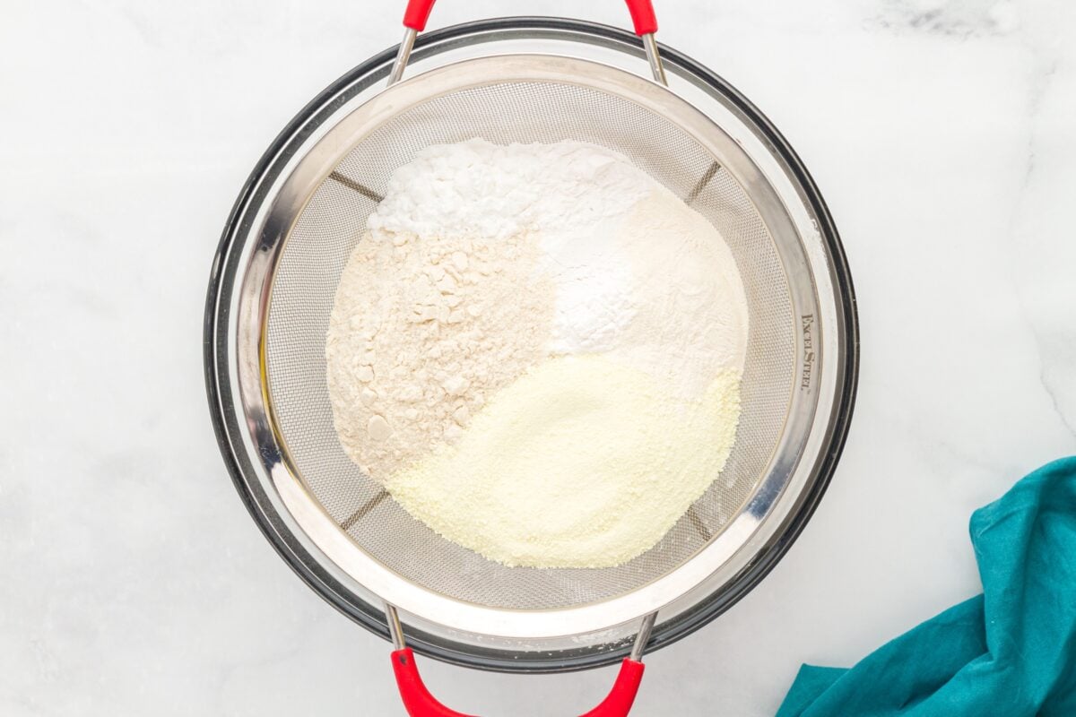 Gluten free flour blend ingredients in a fine mesh strainer before sifting into a bowl