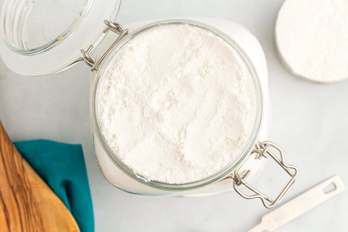 Airtight jar filled with homemade gluten free flour blend on a kitchen counter