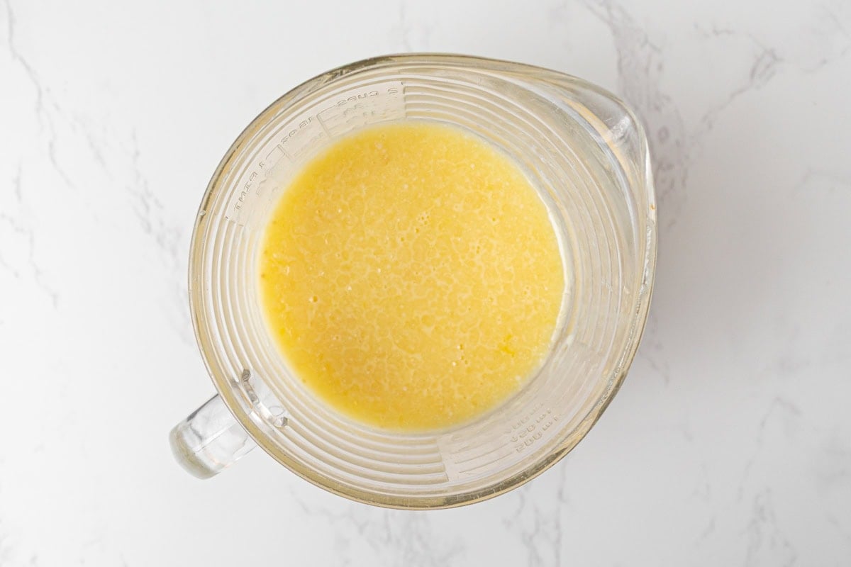 Milk, eggs, melted butter, and vanilla whisked together in a measuring cup for coconut flour waffle batter