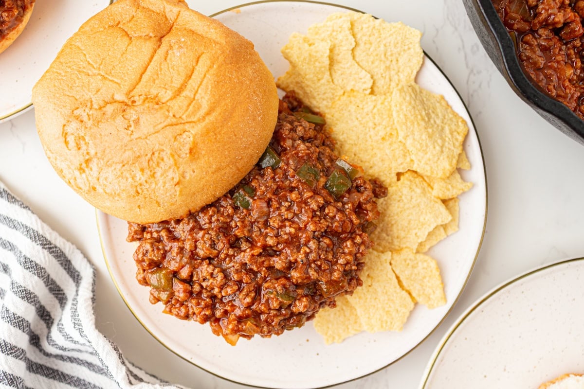 Overhead view of gluten-free sloppy joe sandwich with chips on a plate