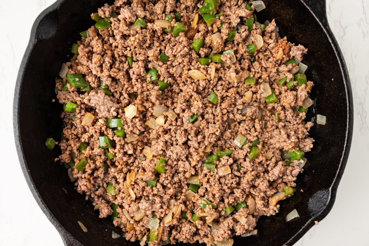 Seasoned ground beef mixture with onions and peppers cooking in skillet