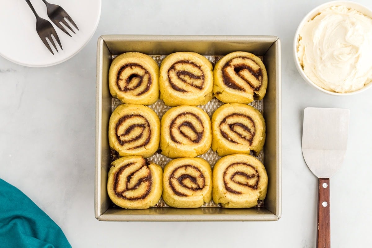 Unbaked keto cinnamon rolls arranged in a square baking pan