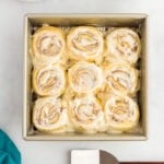 Keto cinnamon rolls in a baking pan topped with cream cheese frosting
