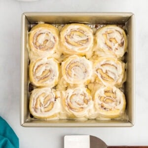 Keto cinnamon rolls in a baking pan topped with cream cheese frosting