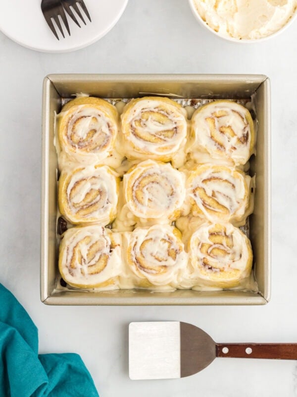 Keto cinnamon rolls in a baking pan topped with cream cheese frosting