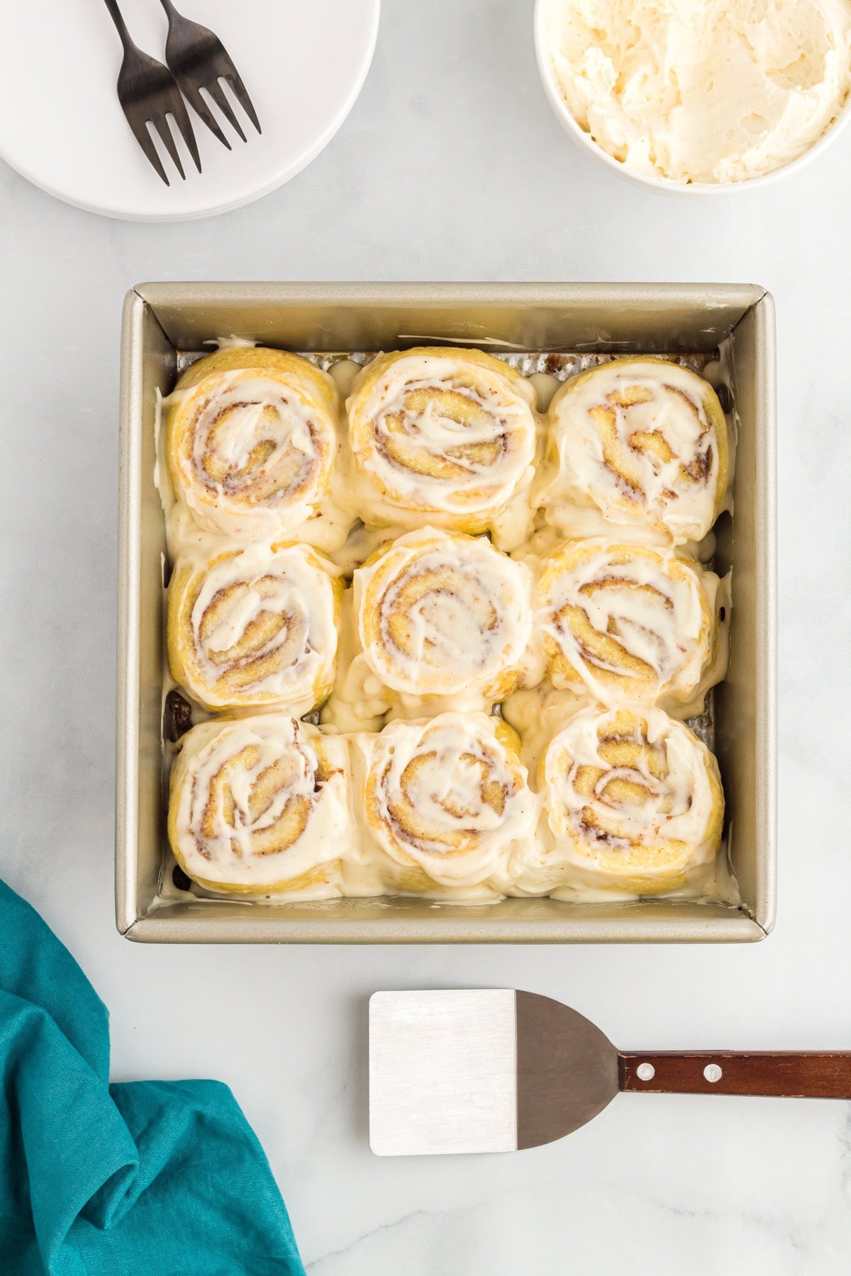 Keto cinnamon rolls in a baking pan topped with cream cheese frosting