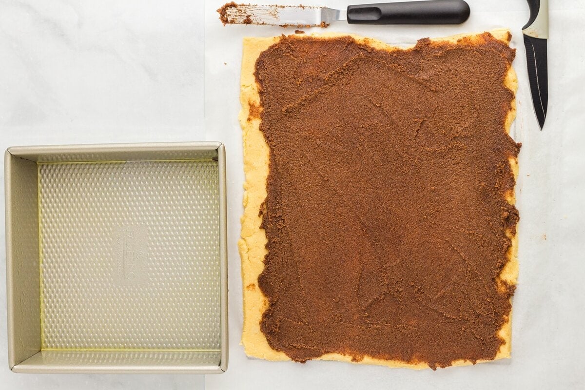 Keto cinnamon roll dough rolled into a rectangle and spread with cinnamon sugar filling before rolling